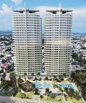 Un hôtel de grande hauteur doté de nombreux balcons, d’une piscine et d’un espace paysager agrémenté de palmiers.