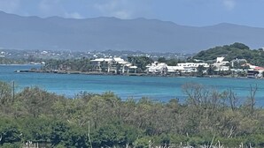 Une ville côtière avec des bâtiments qui bordent le littoral, un ciel dégagé et des montagnes en arrière-plan.