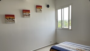 Une chambre avec deux lits, une fenêtre et trois tableaux accrochés au mur.
