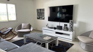 Un salon moderne doté d’un téléviseur à écran plat, de sièges confortables et d’un vase décoratif.