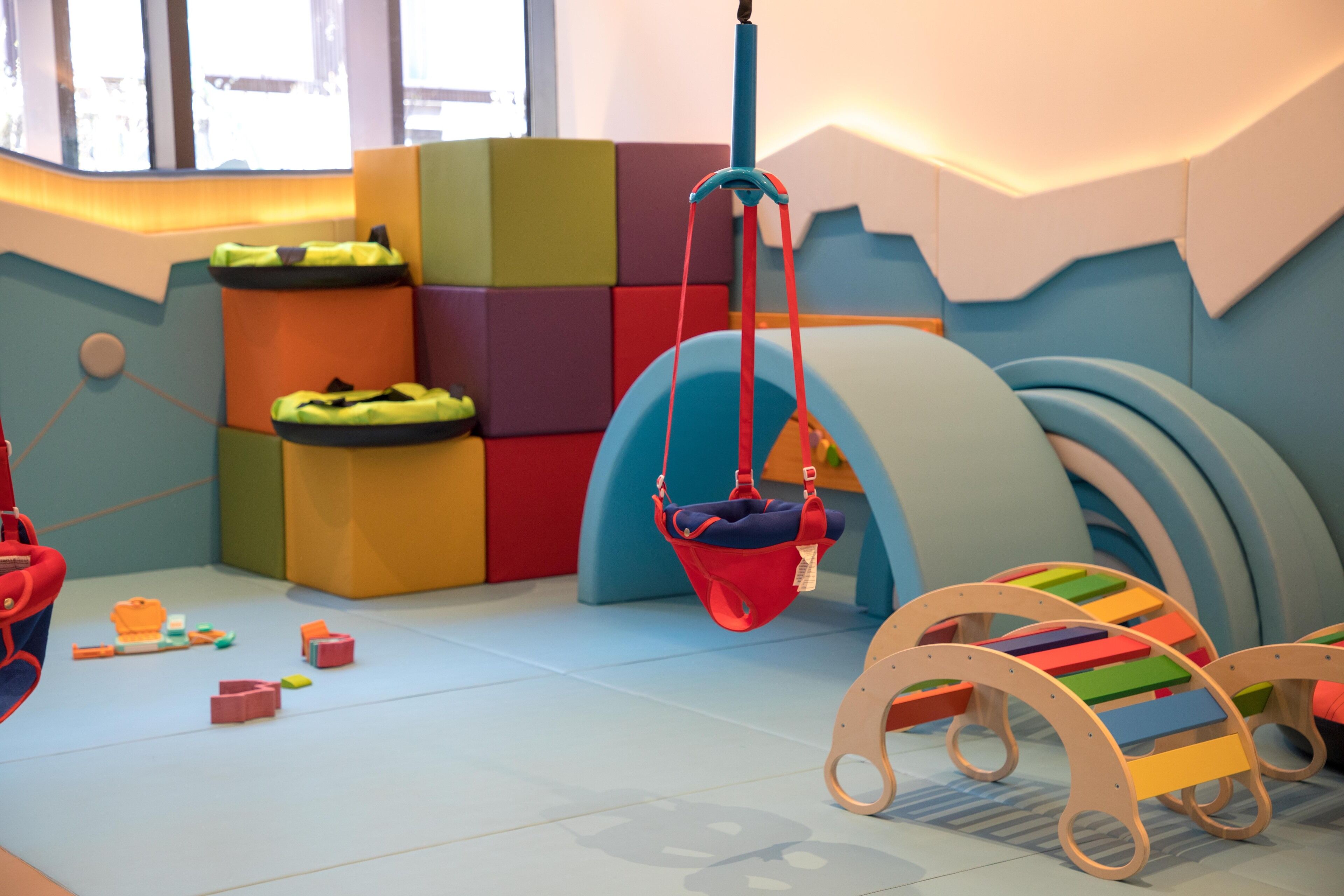 A play area with colorful blocks, a hanging swing, and a wooden slide.