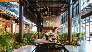 Un amplio atrio con una fuente central, ventanas grandes y columnas de estilo industrial.