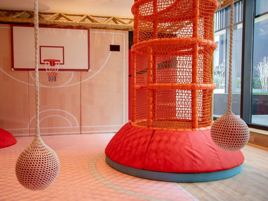 A basketball court with a net, a red cushioned play area, and hanging spherical decorations.