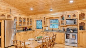 A wooden cabin kitchen with a dining table, chairs, a refrigerator, a stove, and built-in cabinets. - 5 mins to DWTN & Lake, Arcade, Foosball. Best Location in Blue Ridge (Blue Ridge)
