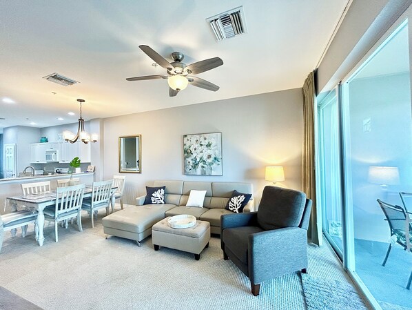 Una sala de estar moderna con ventilador de techo, un comedor con candelabro y un ventanal con vistas.