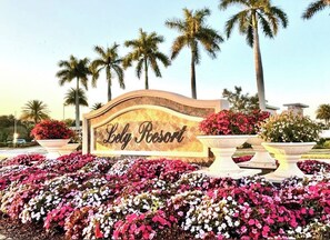 A sign for Lolly Resort with a floral garden in the foreground.