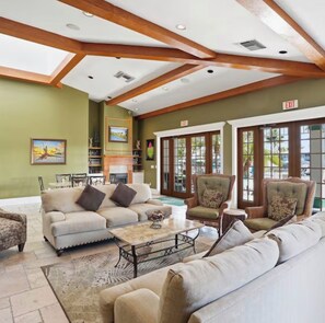 A spacious lobby with a high ceiling, wooden beams, a fireplace, and a view through large glass doors.