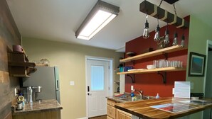 A kitchen with wooden cabinets, a stainless steel refrigerator, a wooden countertop, and a bar area with stools.