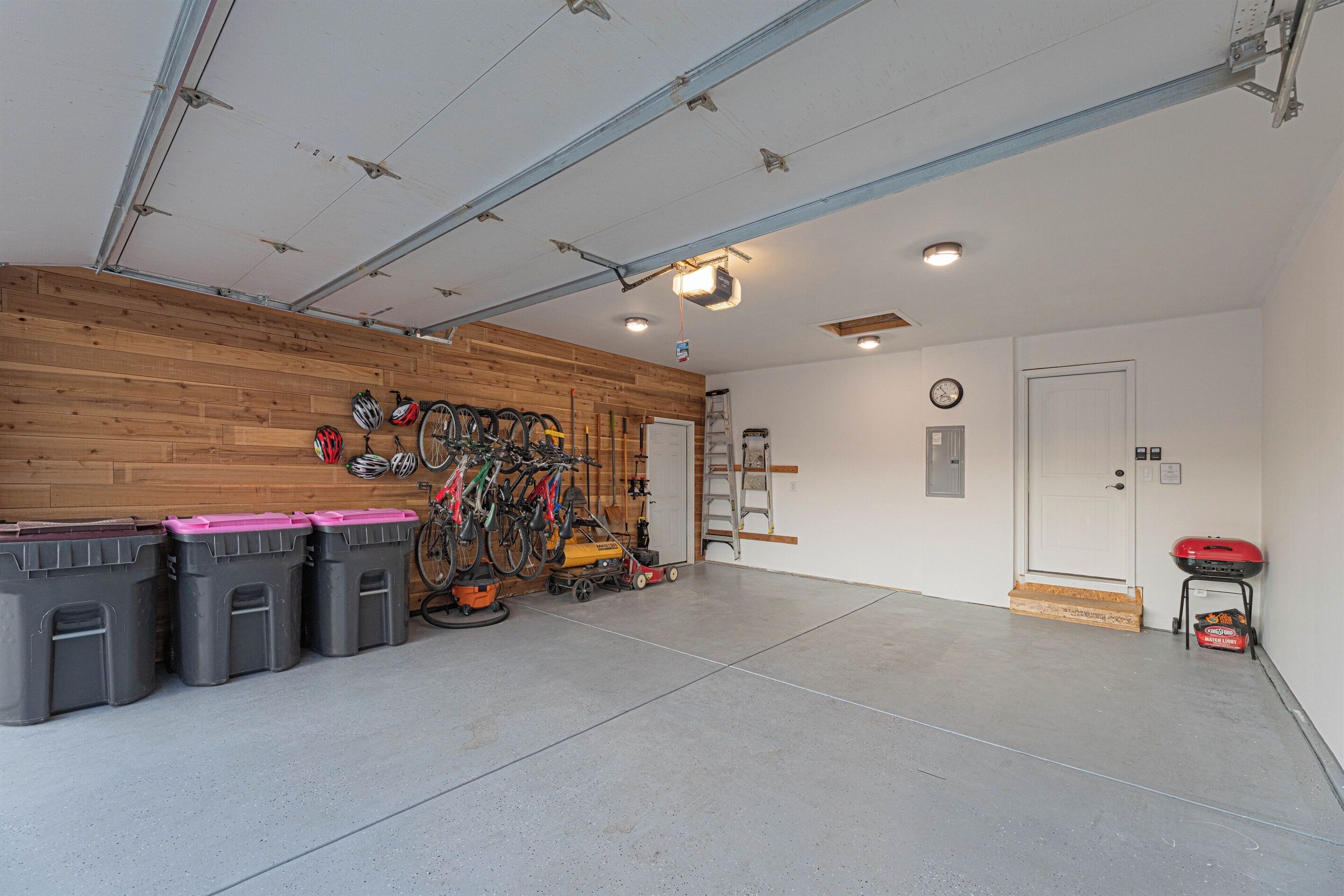 Ett garage med en vägg av trä, ett cykelställ och en röd grill.