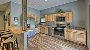 Eine moderne Küche mit Holzschränken, Edelstahlgeräten und einer Bar mit Barhocker.
