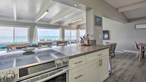 A modern kitchen with a large island, built-in oven, and a view of the ocean. - WFH in Paradise: Beachfront Hauula Getaway! (Hauula)