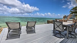 A wooden deck with a table and chairs overlooking a clear blue sea. - WFH in Paradise: Beachfront Hauula Getaway! (Hauula)