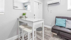 A bathroom with a white vanity, a mirror, and an air conditioning unit on the wall. - Kick back and relax in this calm, stylish space (Fort Lauderdale)