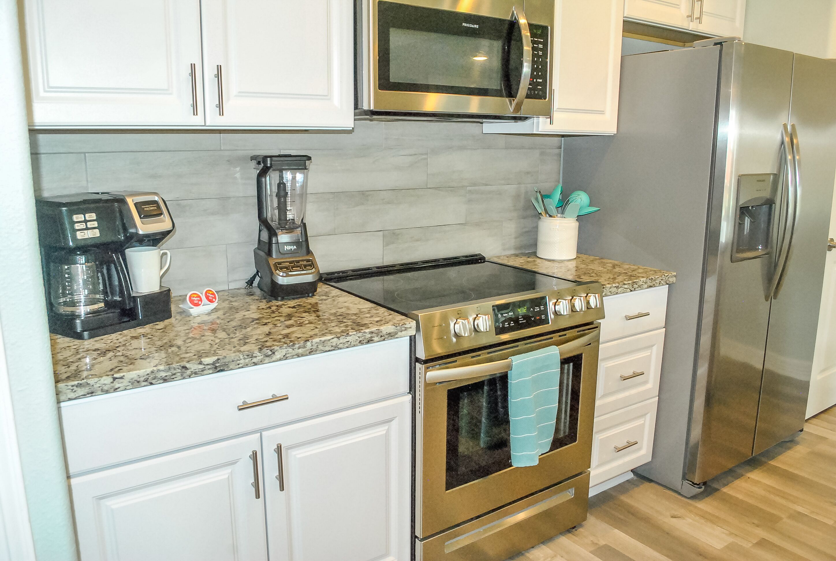 A kitchen with a coffee maker, microwave, stainless steel refrigerator, and a built-in oven.
