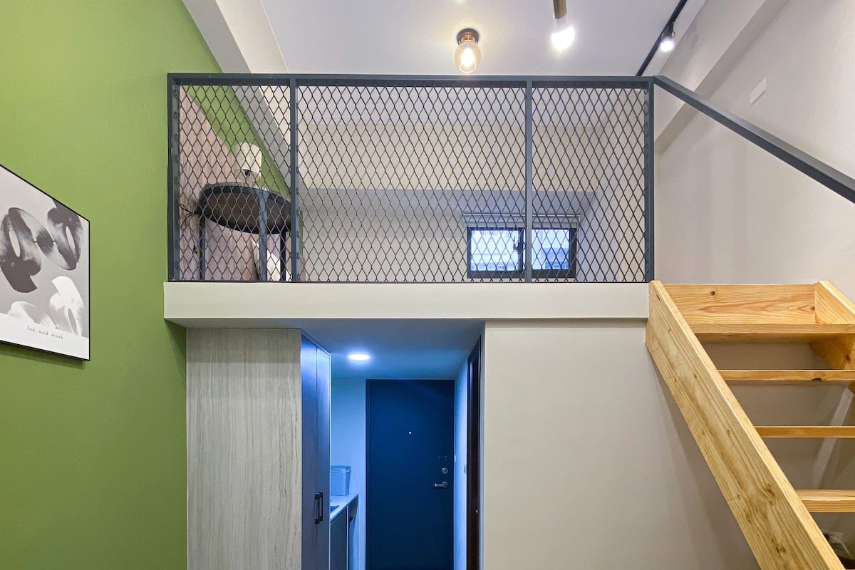A modern interior with a loft bedroom, a staircase, a sofa, and a kitchen area.