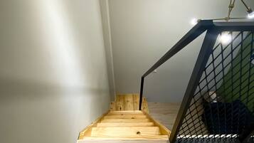 A staircase with a wooden finish and a metal safety barrier at the top.