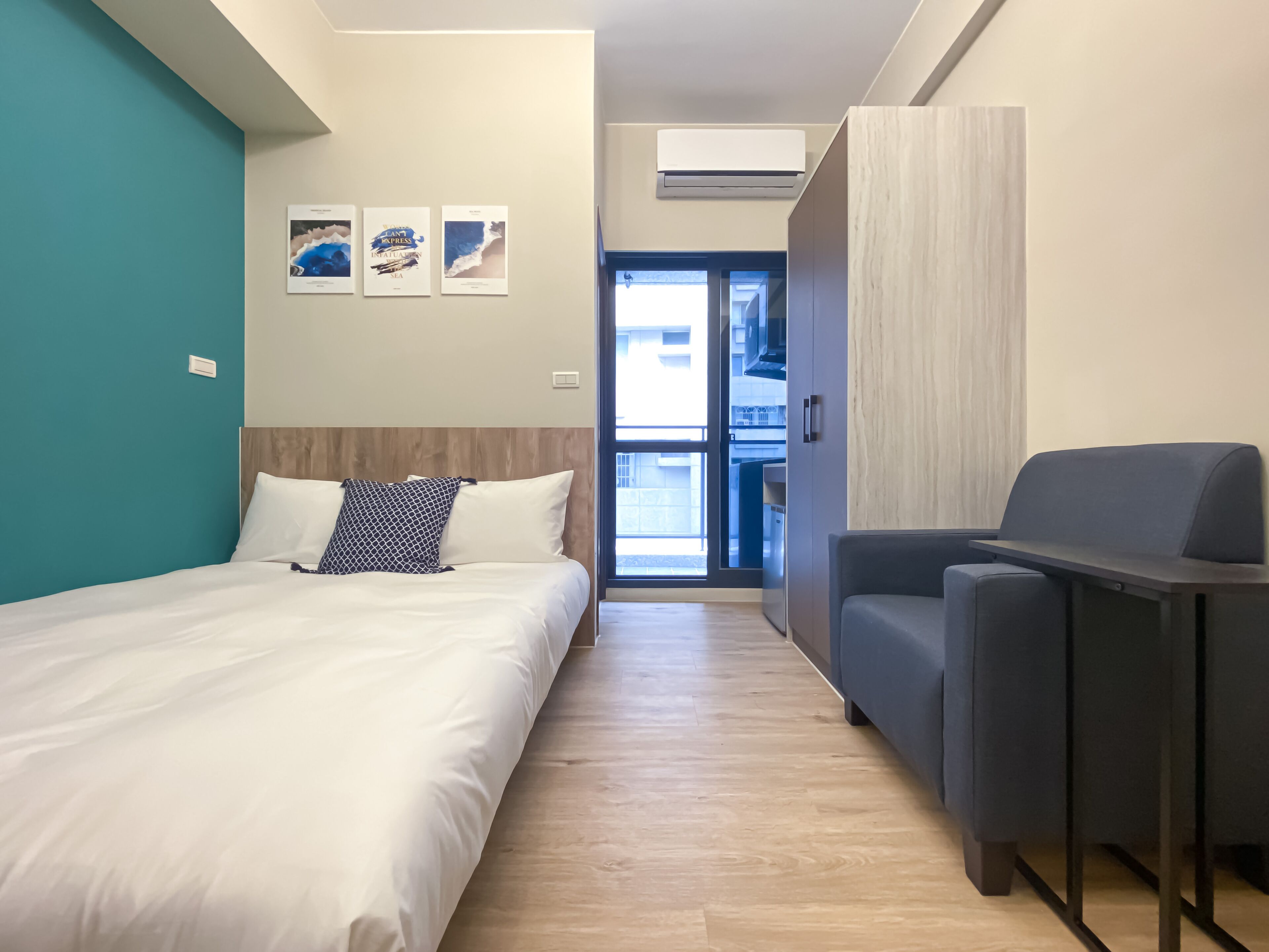 A modern hotel room with a bed, a seating area, and a view of the outside.