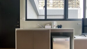Een kitchenette met een inbouwkoelkast, een spoelbak en een raam met uitzicht op gebouwen.