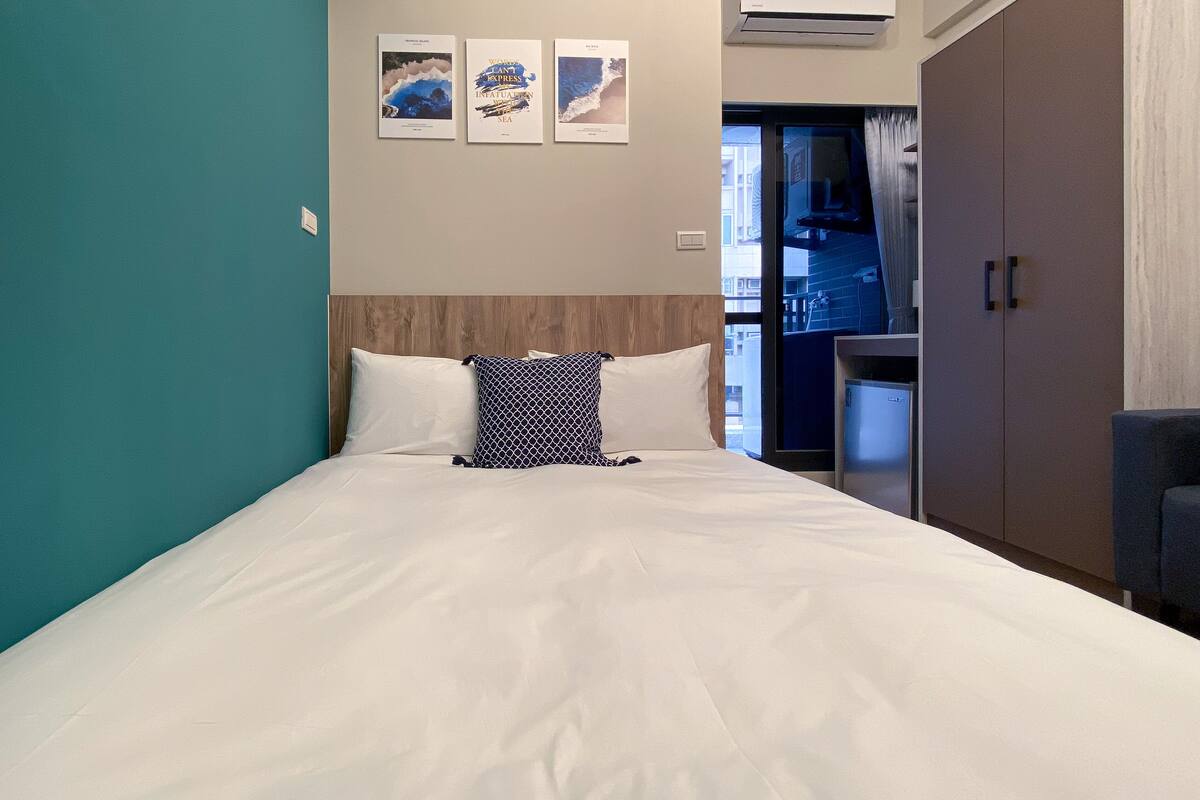 A hotel room with a bed, a wardrobe, and three framed pictures on the wall.