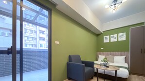 Een moderne kamer met een bed, een stoel, een tafeltje en een groene wand.
