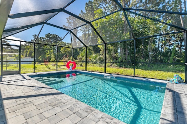 An indoor swimming pool with clear blue water, surrounded by a glass enclosure, and a red inflatable ring in the center.