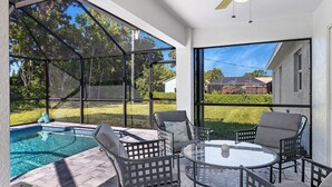 Un patio exterior con piscina, sillas y una mesa.