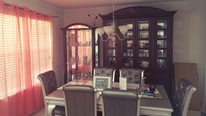 A dining room with a table set for four, surrounded by chairs, a chandelier, and a large wooden cabinet with glass doors. - Welcome to Eve's Place. Come enjoy the historic township of Conyers. (Conyers)