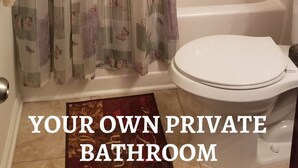 A private bathroom with a shower, toilet, and a curtain with a floral pattern. - Welcome to Eve's Place. Come enjoy the historic township of Conyers. (Conyers)
