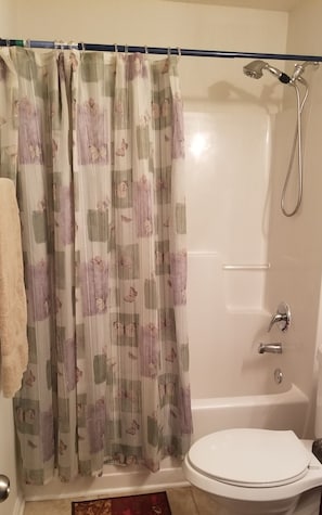 Un baño privado con ducha, inodoro y cortina con estampado floral.