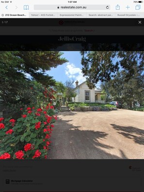 Traditional home with a front yard and pitched roof, surrounded by trees and lush landscaping.