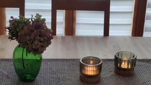 A dining table with a green vase and two lit candles.