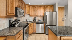 A kitchen with wooden cabinets, stainless steel appliances, granite countertops, and a dishwasher. - Popular Snowmass Condo with HT/Wood FP/Balcony W/Grill/Parking. Great Rates! Plan Your Summer Now! (Snowmass Village)