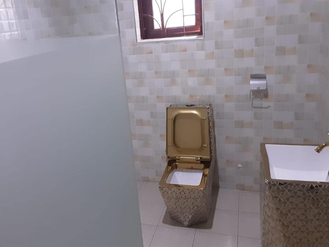 Un baño con inodoro, lavamanos y paredes de azulejos.