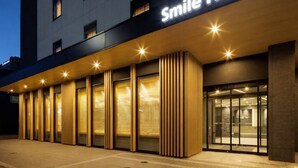 The exterior of the Smile Hotel with a modern facade, large windows, and a prominent illuminated sign. - Smile Hotel Kanazawa Nishiguchi Ekimae (Kanazawa)