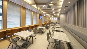 A modern dining area with tables and chairs, large windows with blinds, and a television screen on the wall. - Smile Hotel Kanazawa Nishiguchi Ekimae (Kanazawa)