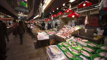 Un mercado animado con varios puestos que ofrecen mariscos, incluyendo pescado y otros productos frescos.