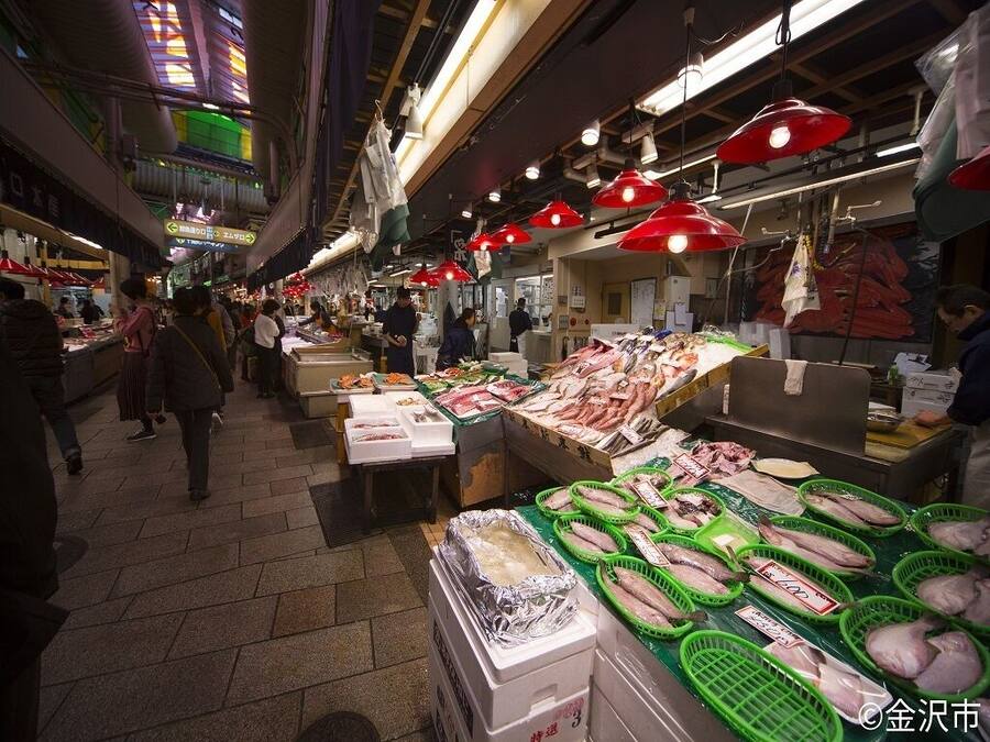 Un mercado animado con varios puestos que ofrecen mariscos, incluyendo pescado y otros productos frescos.