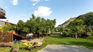 A gravel driveway, a wooden play structure, and a yellow toy tractor. - Maisonette with Timeless Elegance & Panoramic Views (Nals Südtirol)