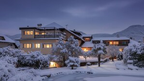 A multi-story hotel with balconies and a snow-covered landscape. - Maisonette with Timeless Elegance & Panoramic Views (Nals Südtirol)