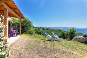 Eine Terrasse mit einer Holzpergola, einem Tisch mit Stühlen und zwei Liegestühlen.