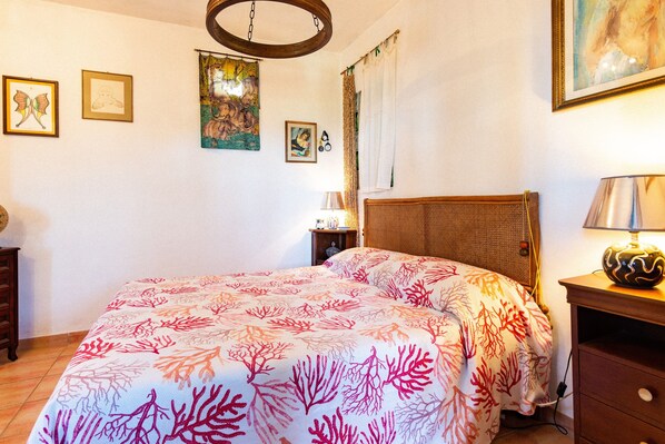 Un dormitorio con cama, mesita de noche, lámpara y decoración en la pared.