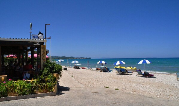 Un restaurant situé en bord de mer, avec une terrasse et des parasols.