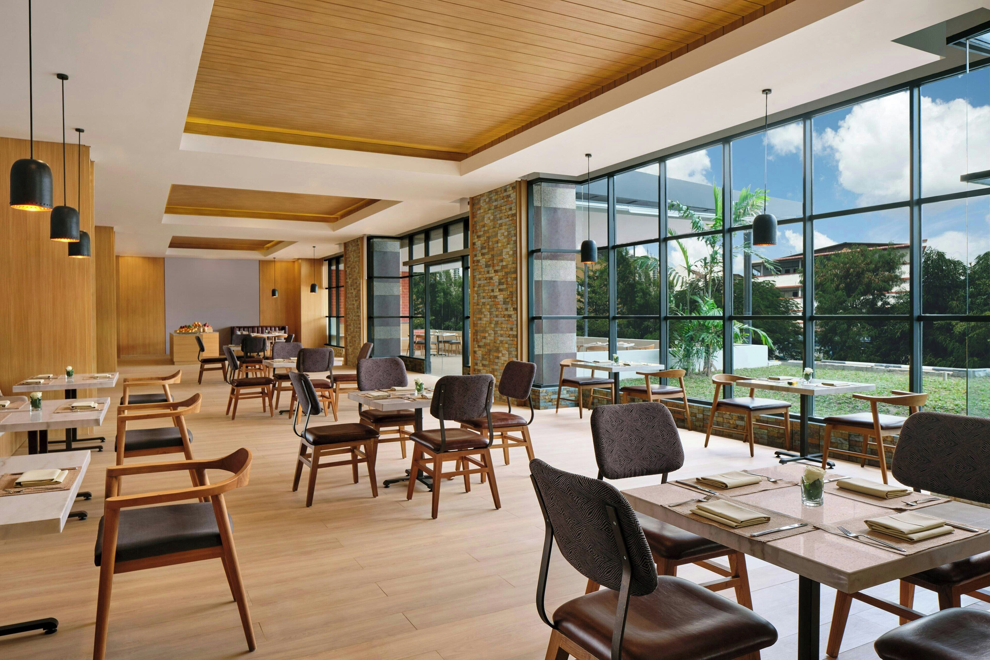 A spacious dining area with large windows, wooden flooring, and modern furniture.