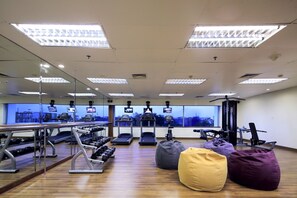 Een sportschool met spiegelwanden, trainingsapparatuur en een groot raam.