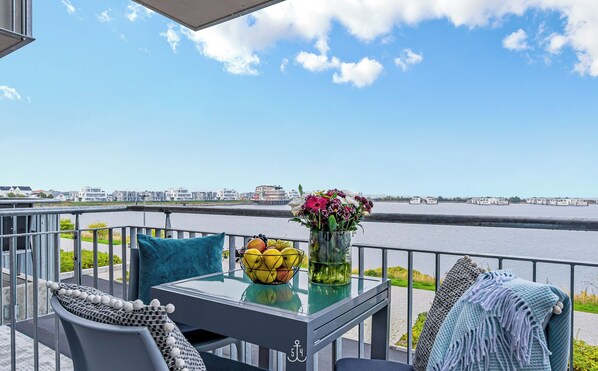 A balcony with a table, chairs, and a view of a river.