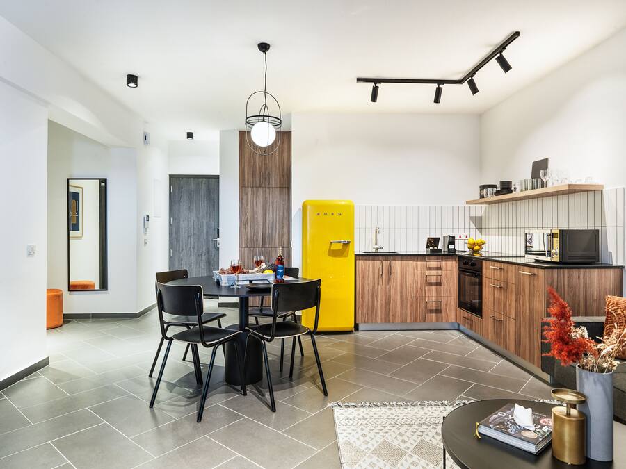 A modern kitchen with wooden cabinets, a yellow refrigerator, and a dining area with a table and chairs.