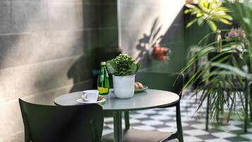 A round table with chairs, a potted plant, a bottle, and a cup.