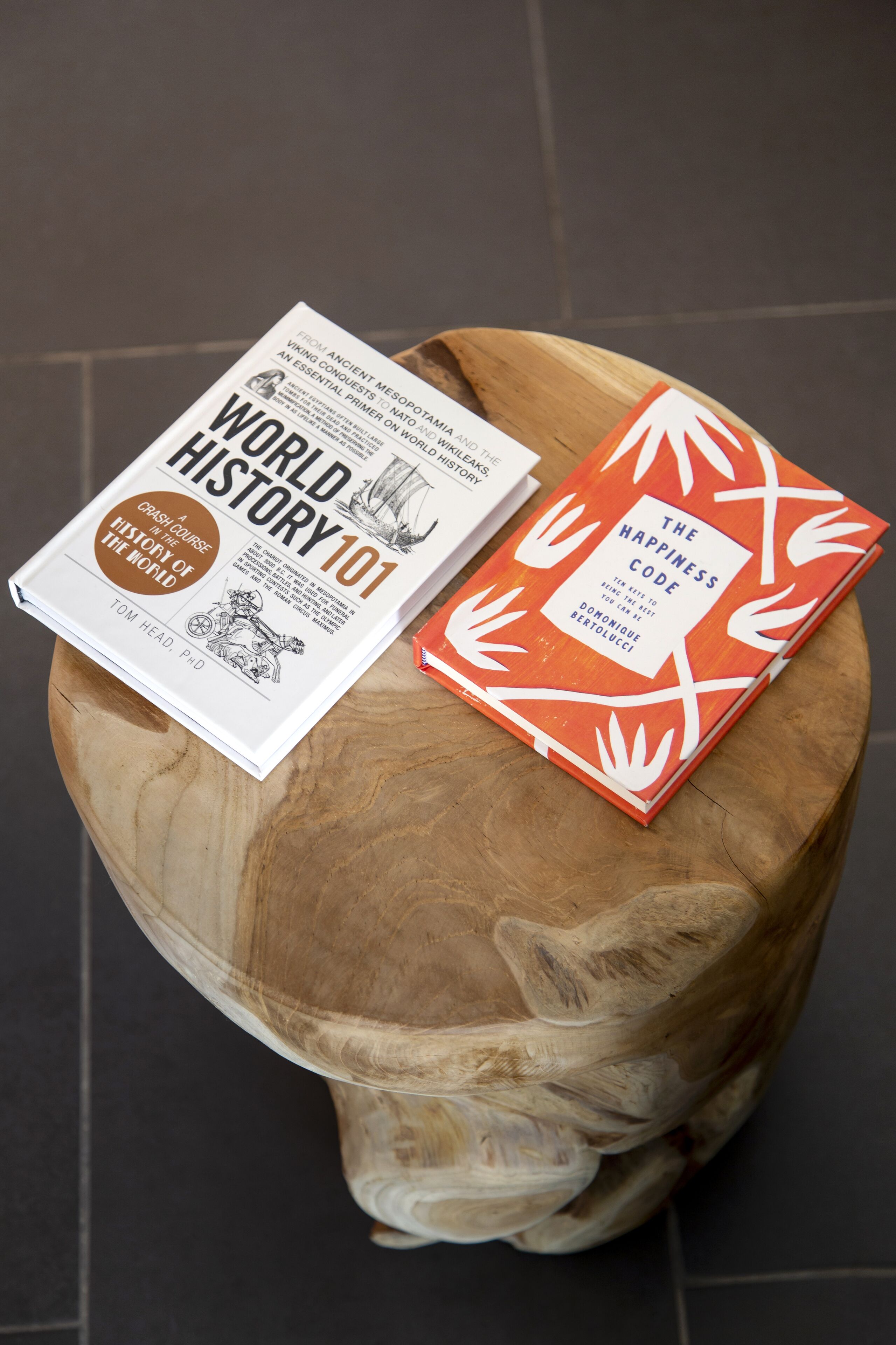 Two books titled 'World History 101' and 'The Happiness Code' placed on a wooden surface.