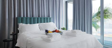 Habitación de hotel con una cama grande, una mesita de noche, una ventana con cortinas y vistas al exterior.