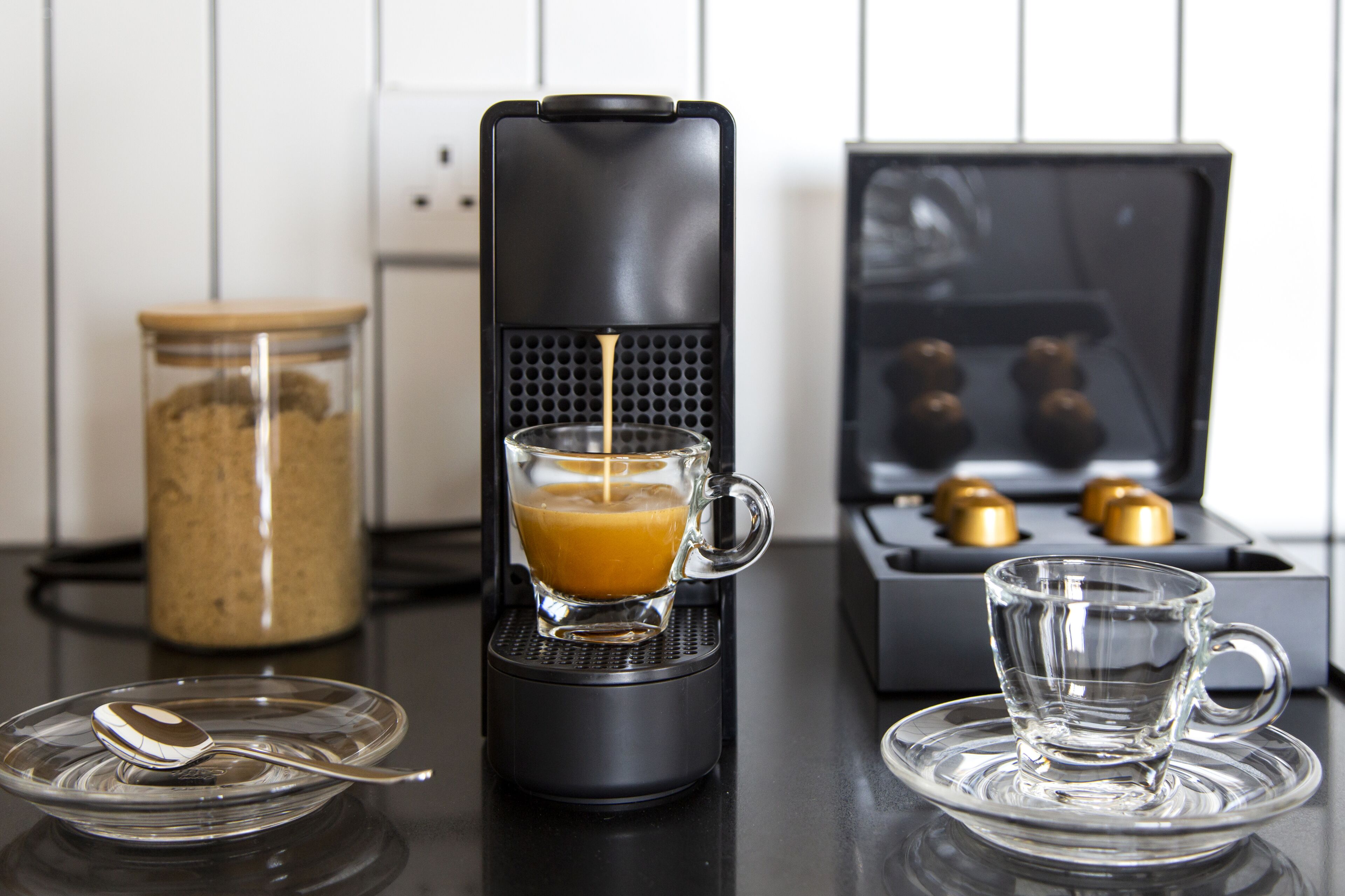 Eine Kaffeemaschine brüht Kaffee in ein Glas, eine Kaffeebohnen-Glas und eine Espressomaschine mit Brühgruppe.